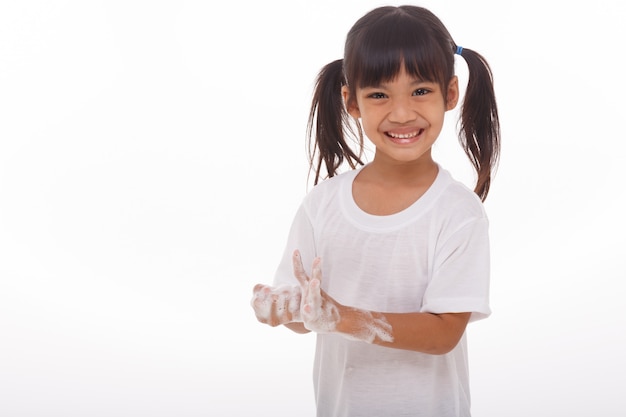 Criança lavando as mãos e mostrando as palmas das mãos com sabão