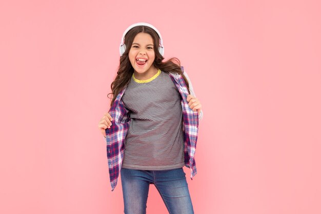 Criança legal ouve música em fones de ouvido em fundo rosa, escola