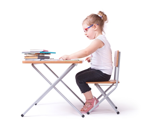Criança lendo um livro sentado em uma cadeira. isolado no branco