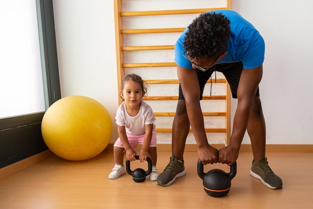 Criança levantando kettlebell com o pai