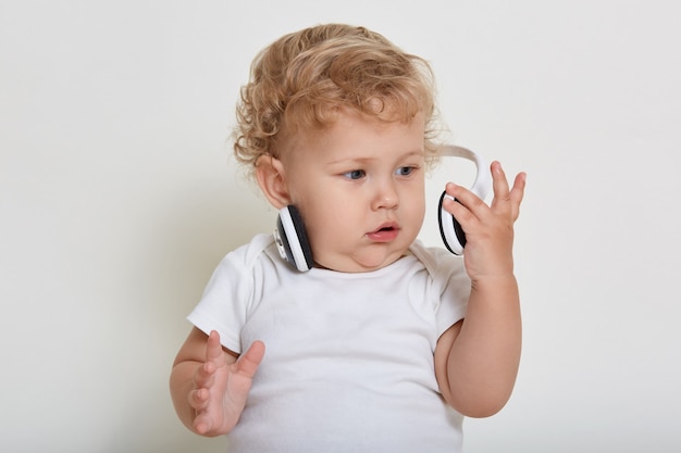 Criança linda em fones de ouvido isolados no espaço em branco, criança estudando um novo assunto interessante