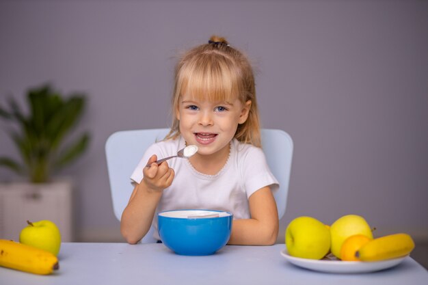 Criança linda menina comendo iogurte dentro de casa