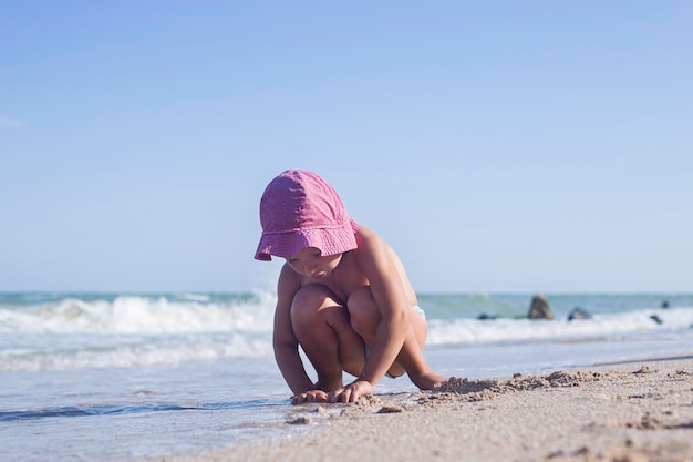 Foto criança loira brinca com areia na praia