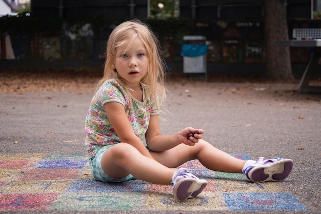 Foto criança loira em idade pré-escolar é jogada sentada no pavimento