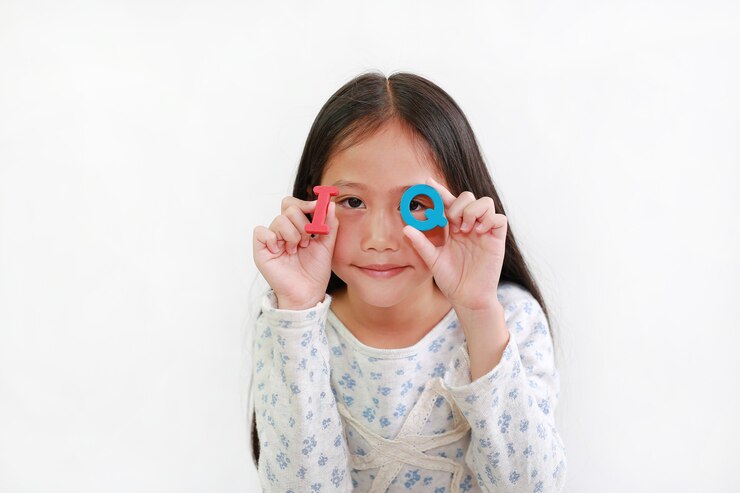 Foto criança menina asiática olhando através do texto de esponja de qi (quociente de inteligência) nas mãos, sobre fundo branco. conceito de educação e desenvolvimento