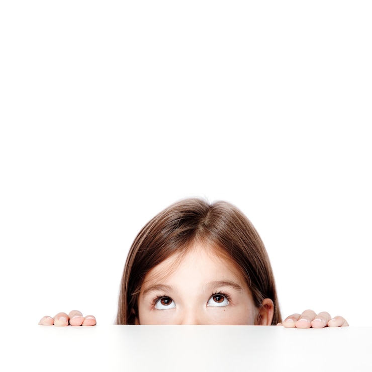 Foto criança menina bonitinha olhando em cima da mesa na escola.