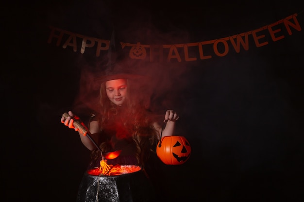 Foto criança menina bruxa preparando uma poção no caldeirão no feriado de halloween