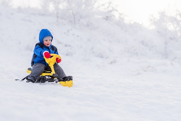 Criança, montando uma scooter de neve no inverno