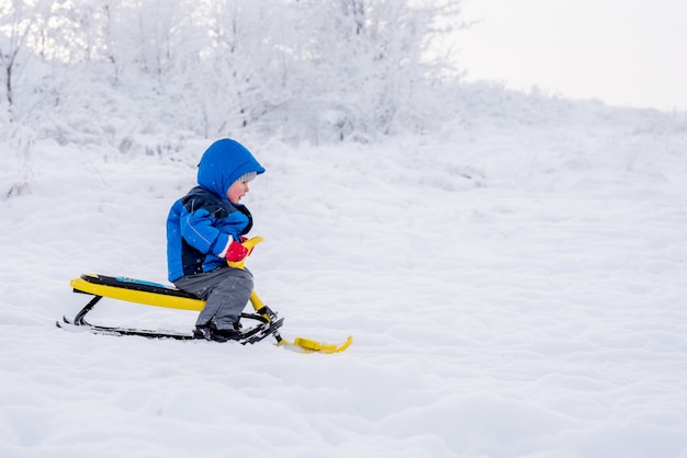 Criança, montando uma scooter de neve no inverno