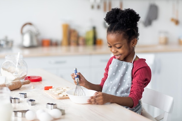 Criança muito afro-americana fazendo massa para pastelaria