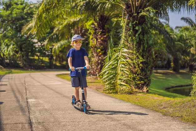 Criança na patinete no parque as crianças aprendem a andar de skate garotinho patinando no verão ensolarado