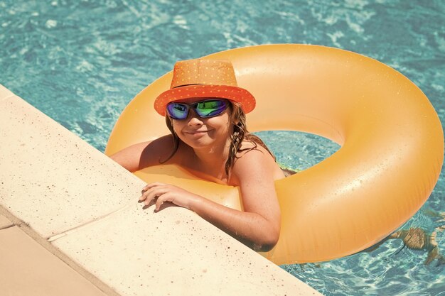 Criança na piscina com anel de brinquedo inflável crianças nadam nas férias de verão natação para criança em flutuador praia mar e água diversão