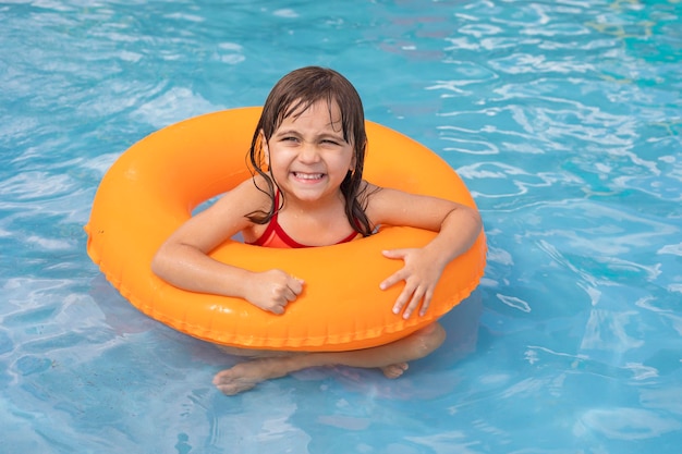 Criança na piscina no anel inflável laranja Menina aprendendo a nadar com anel interno laranja Brinquedo aquático para bebês e crianças Atividade esportiva saudável ao ar livre para crianças Diversão na praia para crianças