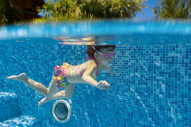 Criança nada na piscina debaixo d'água