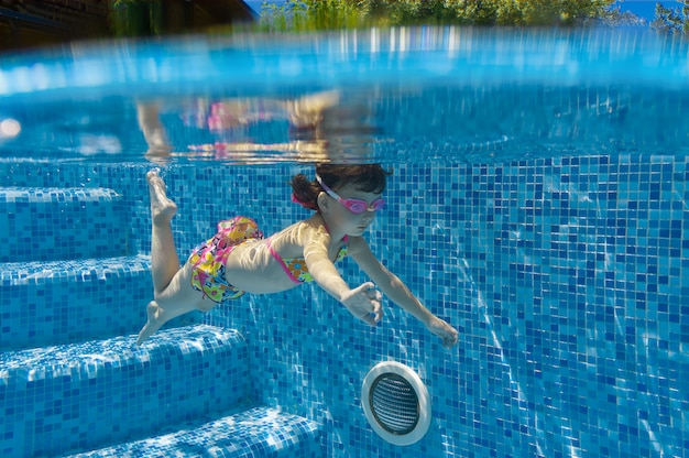 Criança nada na piscina debaixo d'água