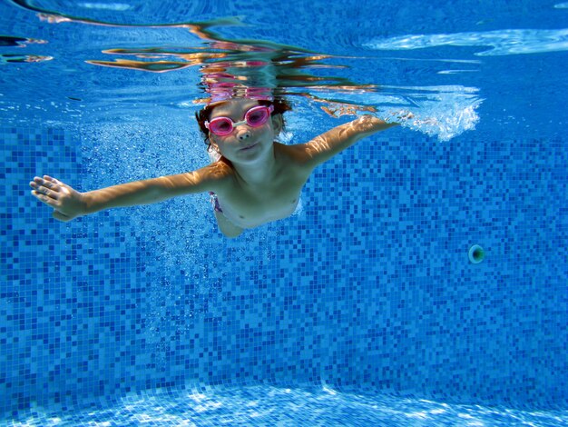 Criança nada na piscina debaixo d'água