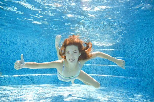 Criança nadando embaixo d'água na piscina