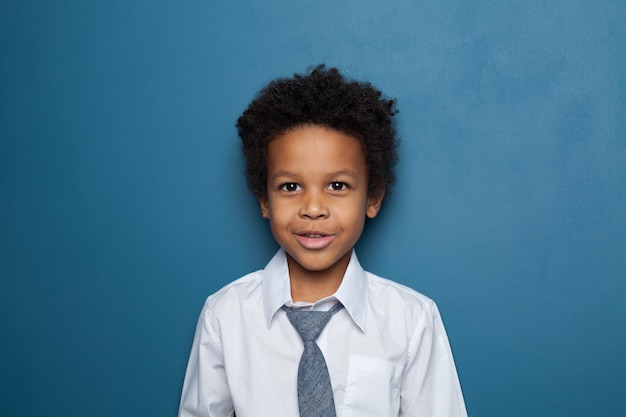 Criança negra afro-americana de camisa branca e gravata em fundo azul