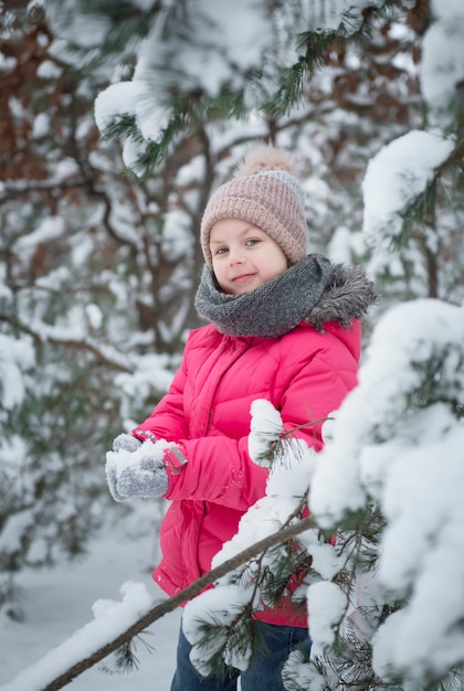 Criança no inverno. Uma menina brincando no inverno lá fora. Um lindo retrato de criança de inverno. Criança feliz, diversão de inverno ao ar livre.