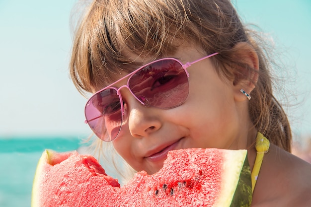 Criança no mar comendo uma melancia. s