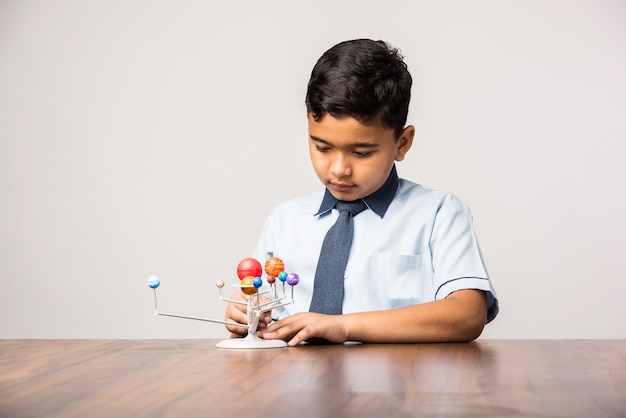 Criança ou menino indiano da escola estudando planetas ou ciências planetárias com o modelo 3d do nosso sistema solar