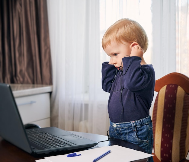 Criança passando o tempo em casa no aprendizado remoto do computador dos pais