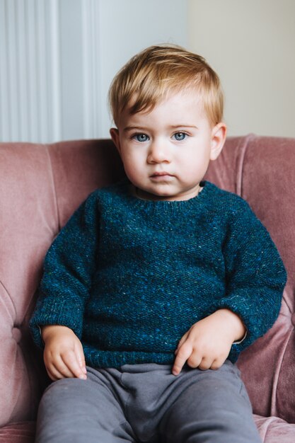 Criança pequena bonita com cabelos claros e olhos azuis, usa blusa e calça