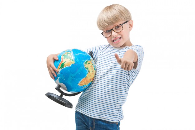 Criança pequena bonito isolada no fundo branco, segurando o globo. Geografia de estudo de estudante. Viagem de garoto bonito. Férias em família com crianças