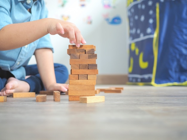 Criança pequena brincando com blocos de madeira no chão