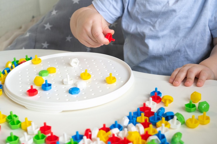 Foto criança pequena brincando com um construtor de mosaico de unhas de cogumelo