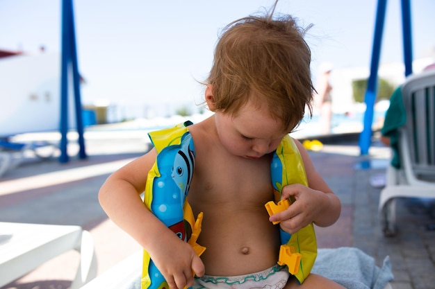 Criança pequena com chapéu panamá joga no verão em dia ensolarado perto da piscina