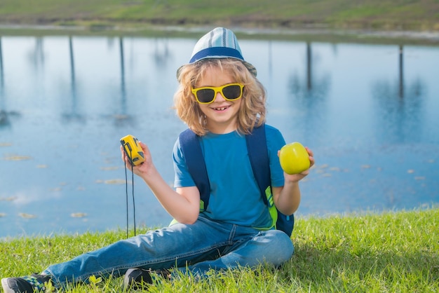 Criança pequena com mochila e binóculos Imaginação ou exploração no parque Criança feliz brincando