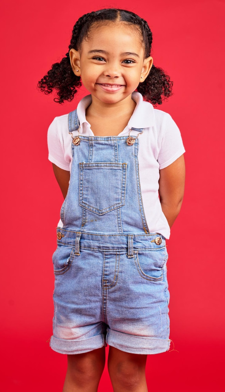 Foto criança pequena e retrato de menina no estúdio feliz e sorriso em fundo vermelho com maquete face alegre e criança na moda em pé contra o espaço animado e positivo sorrindo e posando isolado