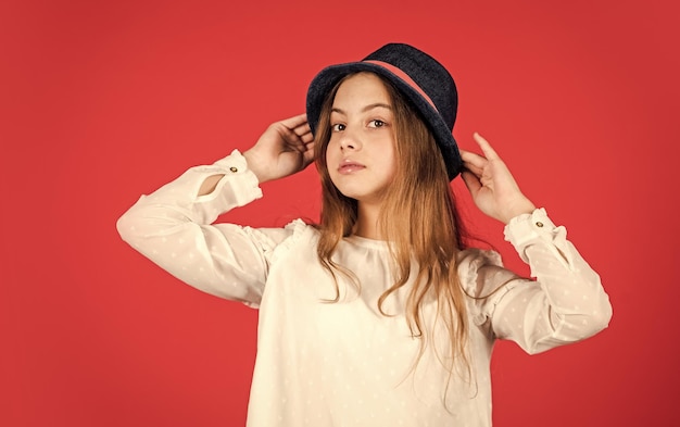 Criança pequena feliz chapéu retrô moda vintage olhar coleção de acessórios de verão criança cabelo comprido beleza e estilo infância feliz Jovem e despreocupada menina retrô fundo vermelho