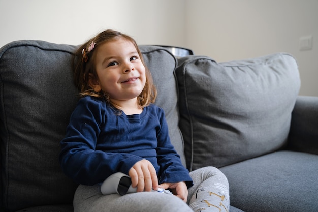 Criança pequena jogando videogame com gamepad no console