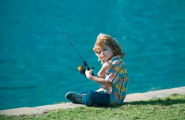 Foto criança pescadora menino com spinner no rio menino pescador menino no cais com raio conceito de pesca