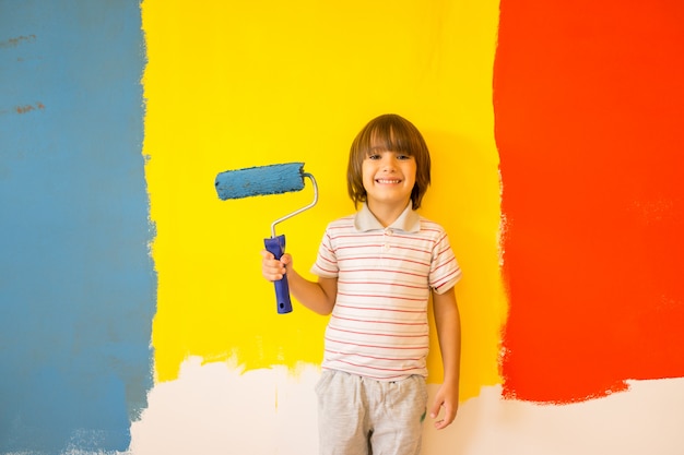 Criança pintando a parede da casa em cores