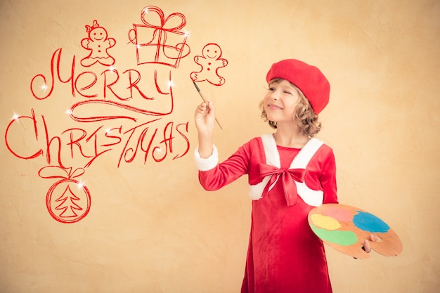 Criança pintando decorações de Natal. Criança brincando em casa. Conceito de férias de natal