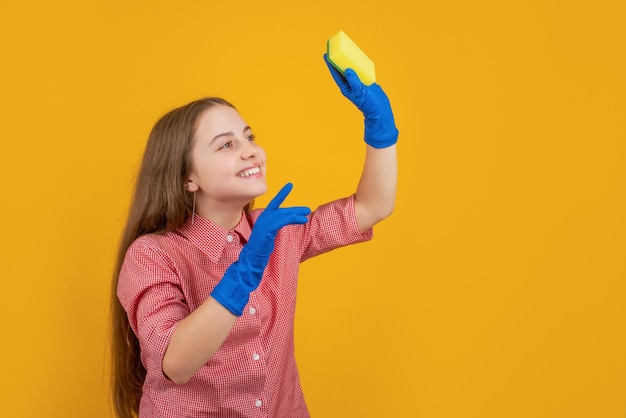 Criança positiva em luvas de borracha com esponja em fundo amarelo