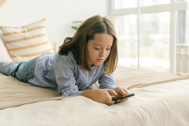 Criança pré-adolescente da escola segurando o telefone, usando o celular para conversar com amigos