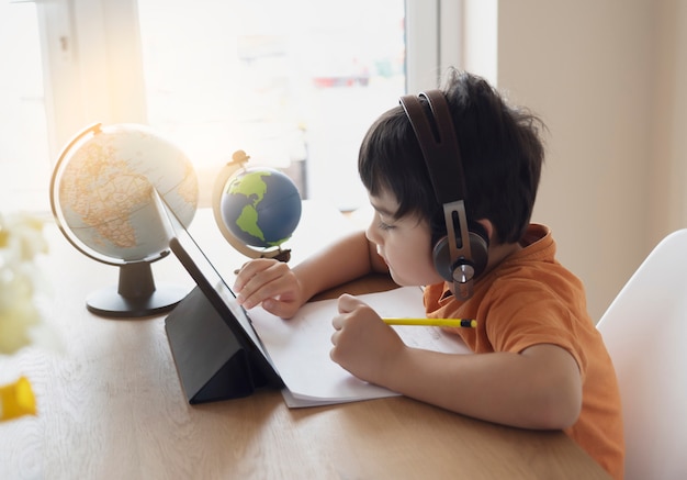 Foto criança pré-escolar usando tablet e usando fones de ouvido