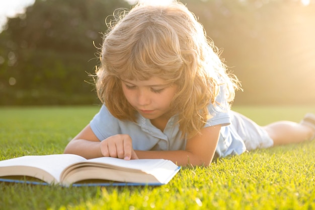 Criança relaxa no feriado, criança lê livros sobre fundo de grama