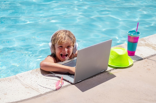 Criança relaxando na piscina com laptop Garoto online trabalhando em laptop nadando em uma piscina de água turquesa ensolarada Trabalho freelance à distância trabalho online elearning