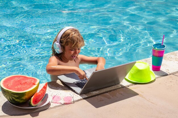 Criança relaxando na piscina usando laptop na água de verão Garoto estudo on-line ou trabalhando na praia do mar tropical Tecnologia para o conceito de vida