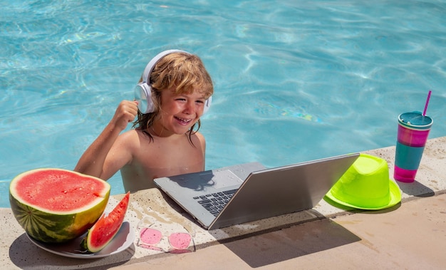 Criança relaxando na piscina usando laptop na água de verão Garoto estudo on-line ou trabalhando na praia do mar tropical Tecnologia para o conceito de vida