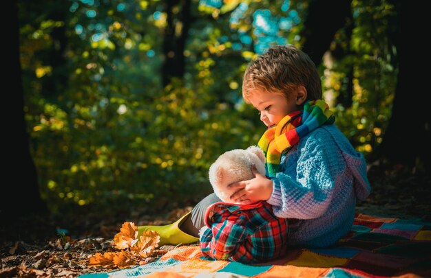 Criança se diverte em atumn Park criança com urso de brinquedo