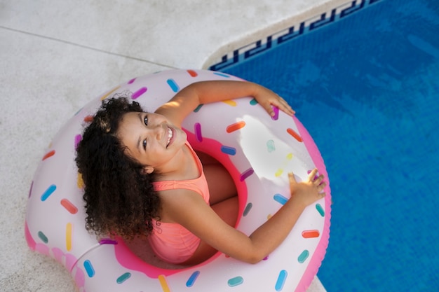 Foto criança se divertindo com flutuador à beira da piscina