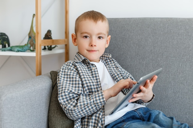 Criança se divertindo com o tablet sentada em um sofá