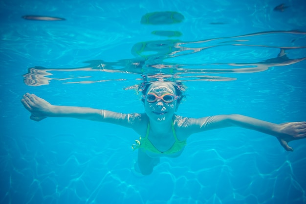 Criança se divertindo na piscina Retrato subaquático de uma criança nas férias de verão