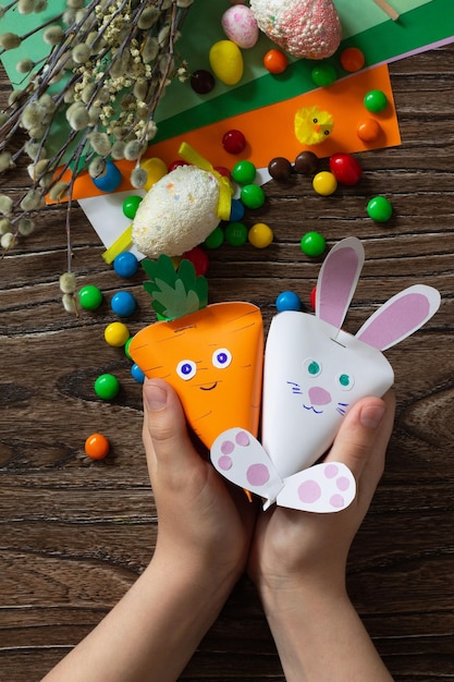 Criança segura a embalagem em forma de cenoura e o coelhinho da páscoa